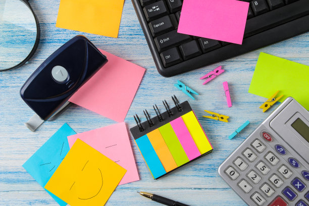 五颜六色的各种便签贴，背景是木制的办公桌子和办公用品。工作场所。图片下载