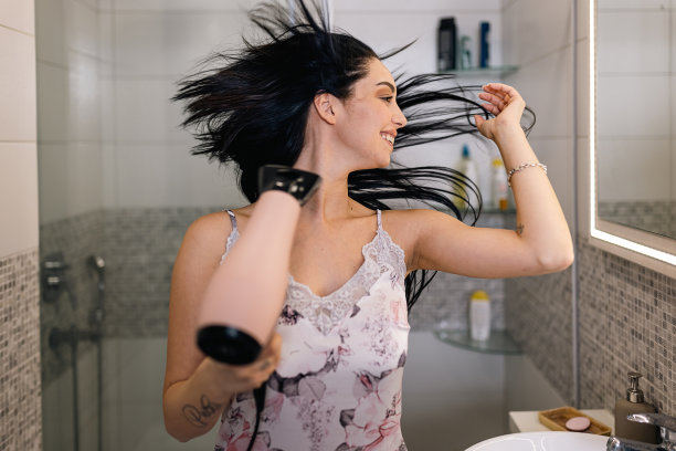 年轻女子用吹风机吹干头发，以全新的自信开始新的一天图片下载