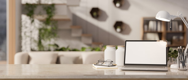 一个现代的工作空间，桌面上有一台笔记本电脑模型，与模糊的现代客厅相对图片下载