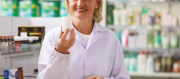女高级药剂师在药店拿着一瓶药的特写图片下载