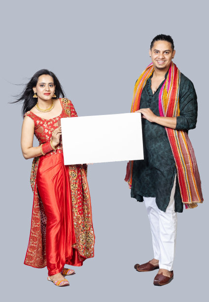 一对印度夫妇手持白板，在节日期间穿着传统服装，在白色的背景下单独站立图片下载