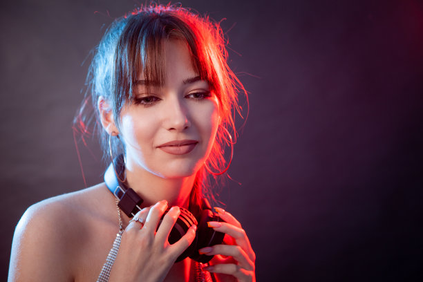 在黑色背景的画室里，一位年轻迷人的白人女性戴着无线耳机图片下载