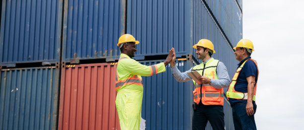 在集装箱货物港，团队工作人员握手示意工作成功。航运、进出口行业内的物流概念。图片下载