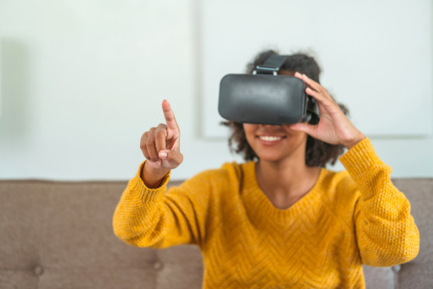 非裔美国少女使用虚拟现实眼镜玩游戏VR模拟器。图片下载