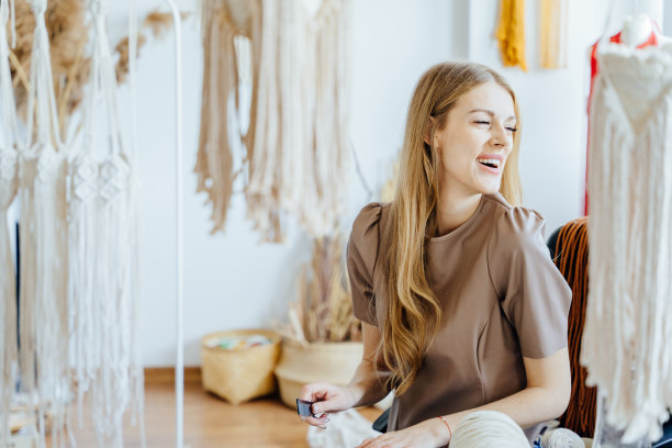 微笑的女工匠在家庭作坊里制作编花的肖像。女编织编织。图片下载