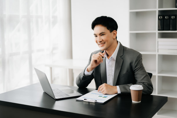 年轻的商人在办公室用笔记本电脑、平板电脑和在纸上做笔记。图片下载