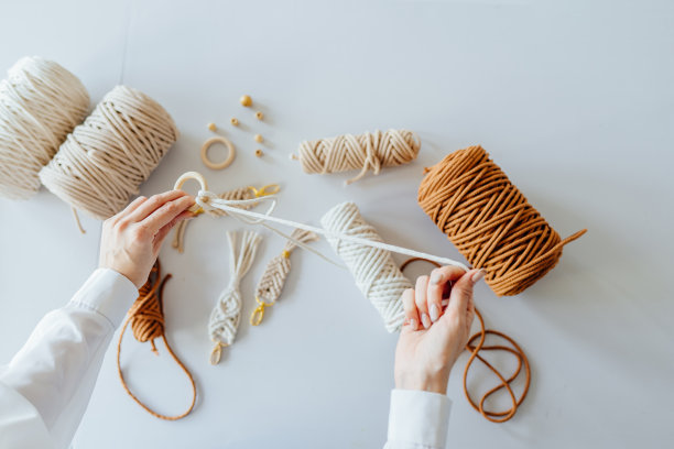 创意爱好手工编织的家庭装饰。妇女的手的特写编织编结。平躺，俯视图。图片下载