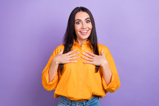 开朗的印象深刻的女人的肖像直发穿超大衬衫手掌在胸前问凝视孤立在紫色的背景图片下载