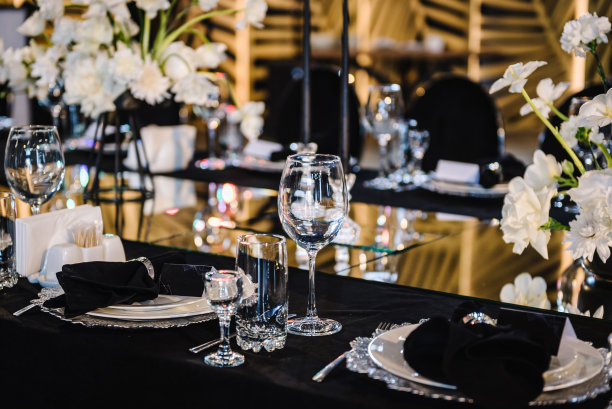 节日装饰与花朵组成，蜡烛在黑色桌布。宴会厅餐厅宴会厅装饰。婚礼准备，宴会区域的餐桌接待。设置。生日，洗礼，大事。图片下载
