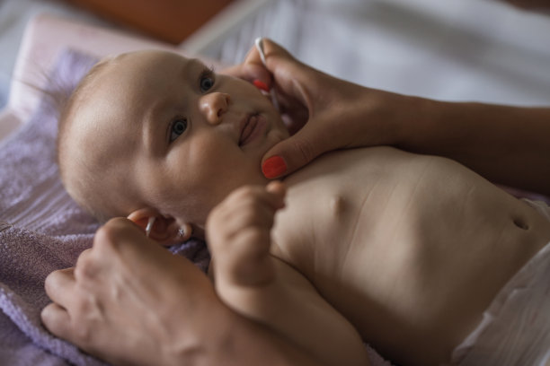 母亲用棉签擦拭新生儿的耳朵图片下载