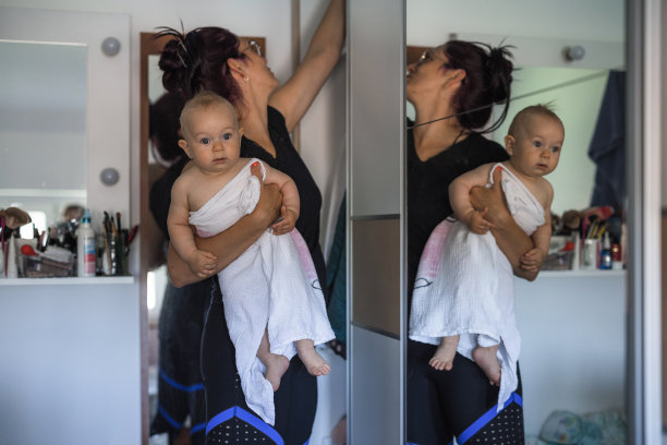 一名妇女抱着洗过的婴儿，在药柜里搜寻图片下载