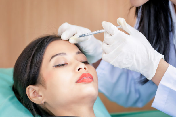 年轻漂亮的亚洲女子在美容诊所接受医生的面部皮肤注射美容治疗。图片下载