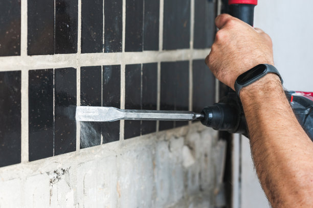建筑工用打孔机拆除混凝土墙上的旧瓷砖图片下载