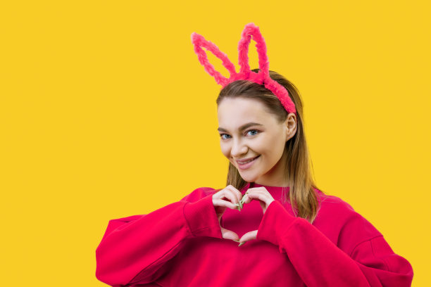 黄色背景上戴兔耳朵的年轻女子图片下载