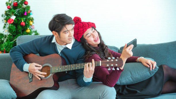 幸福的情侣相爱。年轻时髦的时尚夫妇在室内令人惊叹的性感肖像。年轻人在为他心爱的女孩弹吉他。图片下载