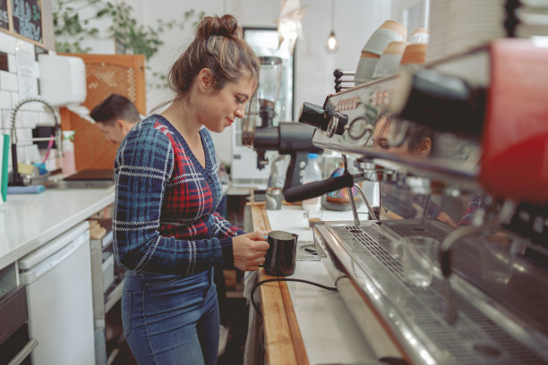 站在吧台为咖啡准备牛奶的女咖啡师图片下载