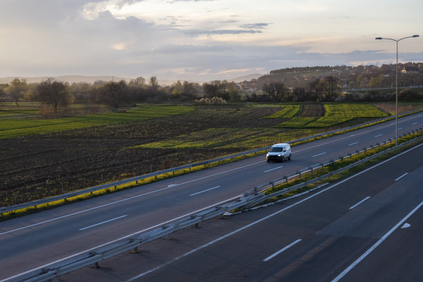 高速公路上的白色货车。白色现代快递小件货物快递车在高速公路上快速行驶到城市郊区。世界上最好的货物运输。图片下载