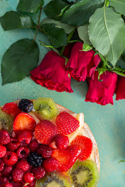 平坦的红花玫瑰和美丽美味的甜蛋糕浆果在绿色的背景。图片下载