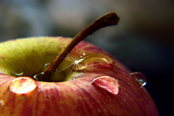 苹果上闪亮的水滴的特写镜头光晕和浅景深与美丽的散景背景。图片下载