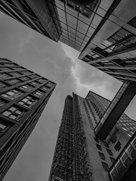 低角度的现代摩天大楼映衬着多云的灰色天空图片下载