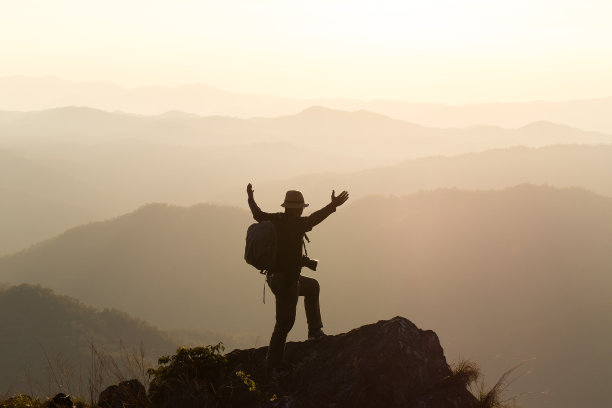 人的剪影在山峰上举起双手，成功的概念图片下载