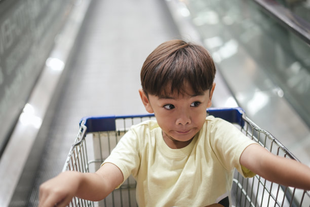 小男孩坐在超市的手推车里图片下载