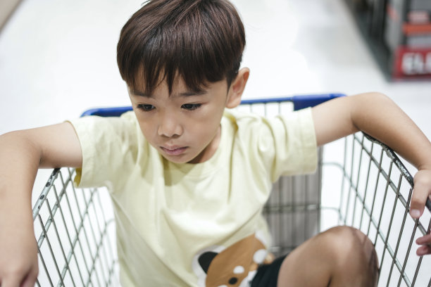 小男孩坐在超市的手推车里图片下载