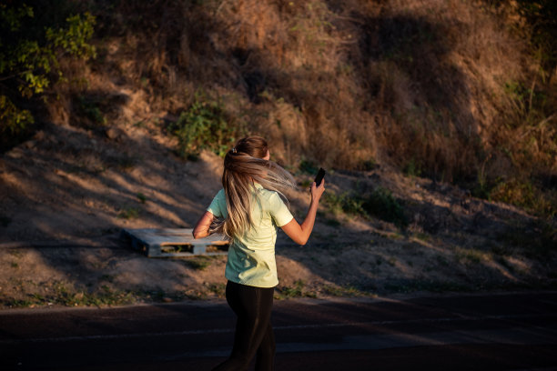 穿着运动服的苗条女孩正在慢跑，手里拿着智能手机。女商人在打电话图片下载
