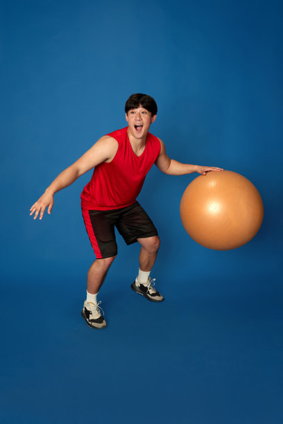 穿着运动服训练的年轻马的全身画像，在蓝色的工作室背景下玩健身球图片下载
