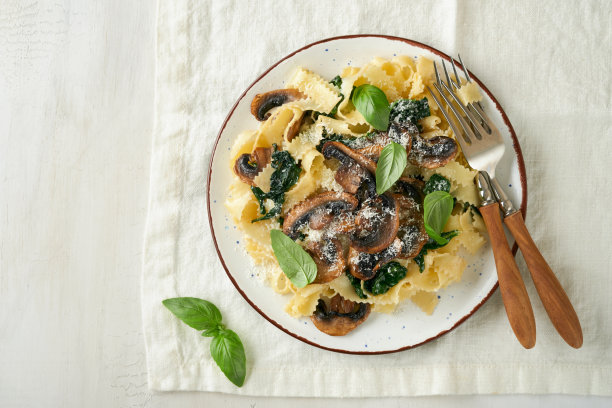 奶油阿尔弗雷多意大利面。意大利意式宽面，加蘑菇、鸡肉、菠菜、罗勒和奶油酱，背景为白色石头或混凝土。传统的意大利菜。平的。本空间图片下载