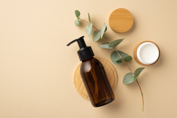 天然化妆品的概念。顶视图照片的玻璃瓶，奶油罐桉树和木制的立场上孤立的米色背景图片下载