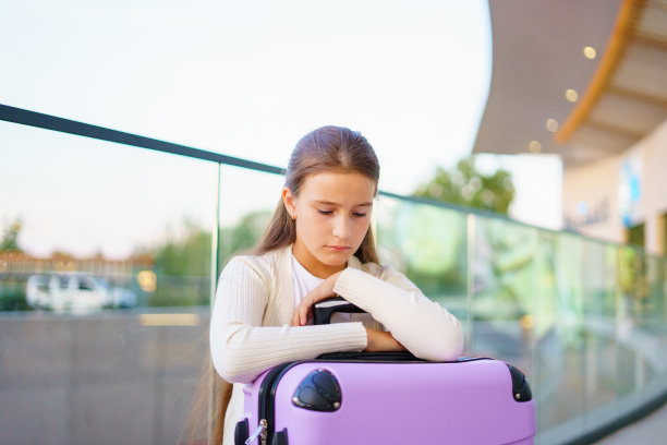 可爱的小女孩提着行李箱在候机楼外等候图片下载