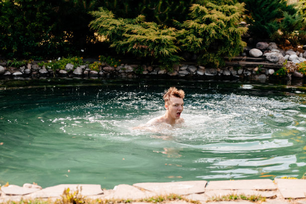 泳池里的那个人。一个男人正在池塘里游泳。湖中美丽的照片图片下载