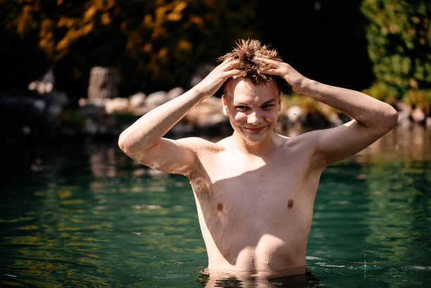 泳池里的那个人。一个男人正在池塘里游泳。湖中美丽的照片图片下载