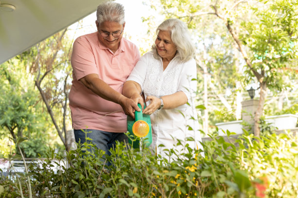 快乐的老夫妇在花园里浇花。图片下载