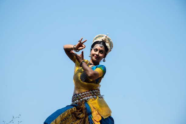 印度女子奥黛西舞者在晴朗的蓝天下表演古典舞蹈。Orissi跳舞。印度的艺术和文化。低角度拍摄。图片下载