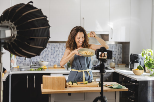 成熟女人在家做饭为社交媒体制作视频，数字内容创作者，博主。图片下载