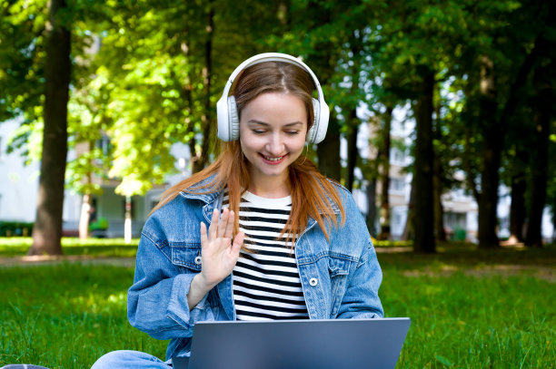 年轻快乐的红发女孩戴着耳机在网上交流。工作电话或在线学习小组。远程工作或电子学习图片下载