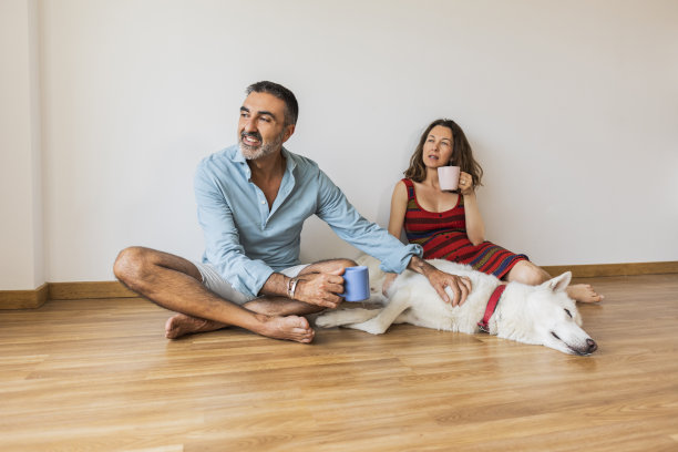 一对成熟的夫妇带着他们的狗坐在家里的地板上，一边喝着轻松的咖啡图片下载