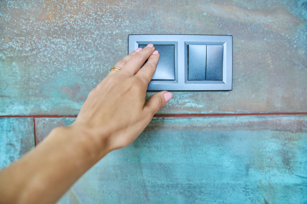 现代的黑色电器开关挂在墙上，女人的手触摸着开关图片下载
