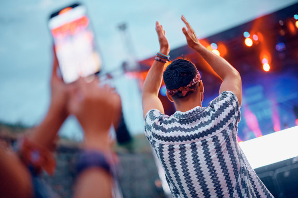 一名男子在露天音乐会上拍手的后视图。图片下载