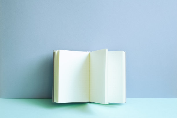 打开蓝色桌子上的笔记本。蓝墙背景图片下载