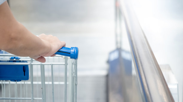 在杂货店或超级市场的自动扶梯上，顾客手持购物车。图片下载