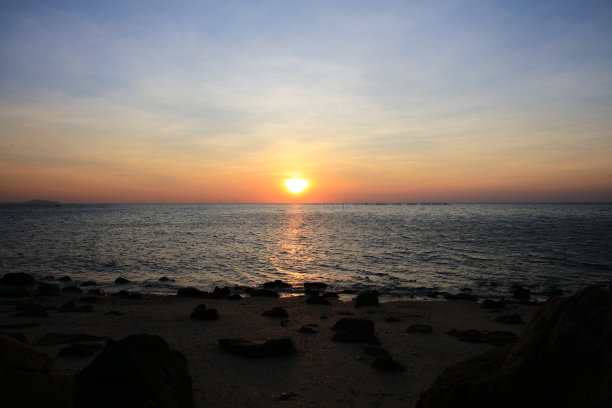 暑假，蔚蓝的大海上，自然的海景落日。海滩上夕阳的剪影图片下载