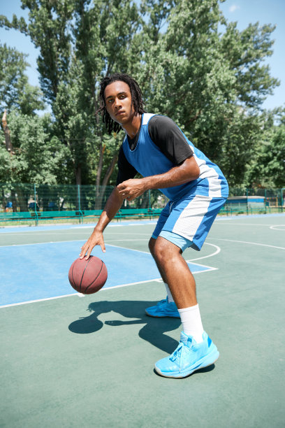 在阳光明媚的日子里，穿着蓝色制服的篮球运动员在操场上进行户外训练图片下载