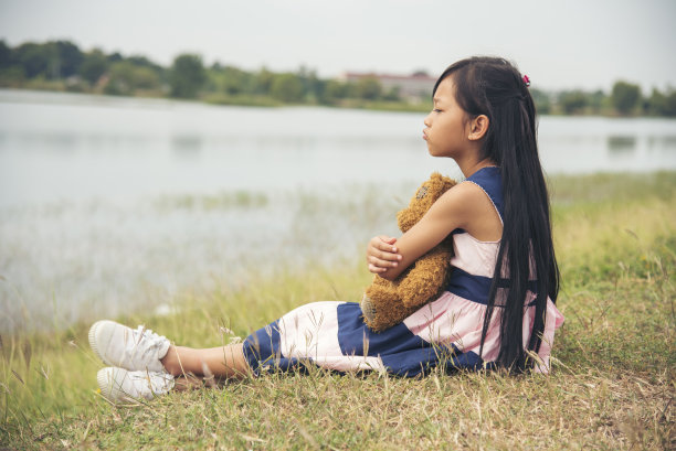 快乐的孩子在绿色公园操场上拥抱泰迪熊。泰迪熊是小朋友们最好的朋友，可爱的女孩。自闭症在操场上快乐玩耍，在幸福的家庭里感受爱和温暖的拥抱图片下载