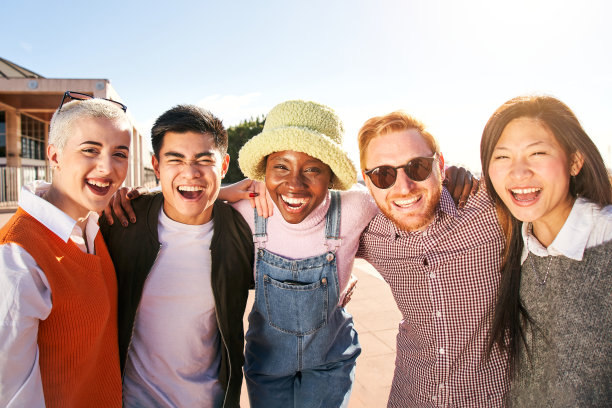 多种族学生的肖像，他们很开心地拥抱，笑了很多。他们在户外欢笑图片下载