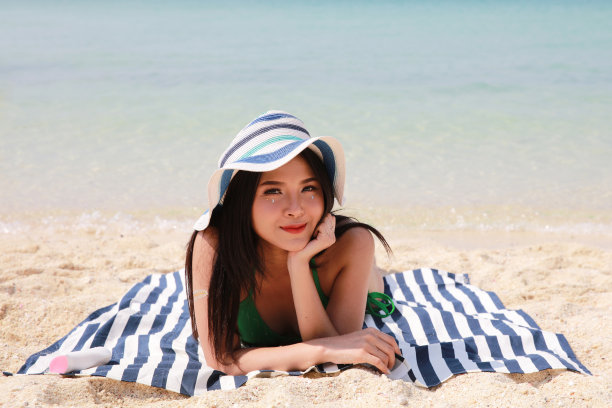 亚洲性感女性沙滩日光浴，夏日沙滩度假概念图片下载