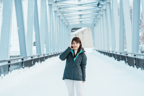 女人旅游参观Biei,旅行者在毛衣观光Shirahige瀑布桥冬天下雪。它是日本北海道的地标和著名景点。旅游度假概念图片下载