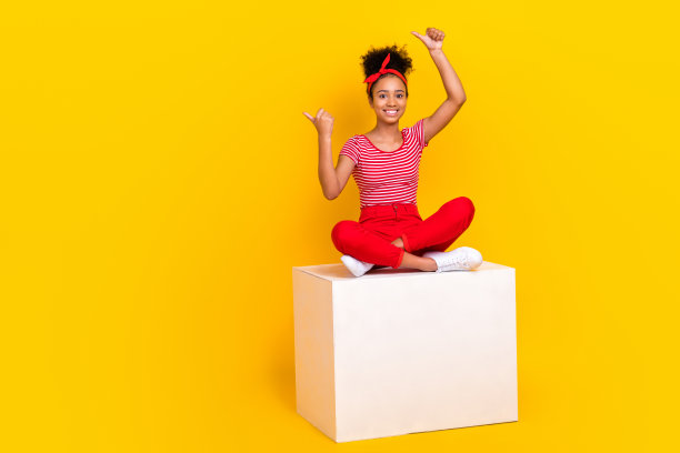 可爱兴奋的女孩穿着红色条纹t恤指着两个大拇指空白的空间孤立的黄色背景的全身照片图片下载